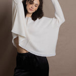 A woman wears an oversized 100% cashmere sweater in Ivory with black silk trousers