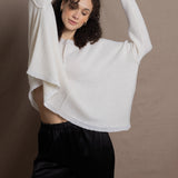 A woman wears an oversized 100% cashmere sweater in Ivory with black silk trousers