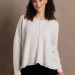 A woman wears an oversized 100% cashmere sweater in Ivory with black silk trousers