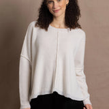 A woman wears an oversized 100% cashmere sweater in Ivory with black silk trousers