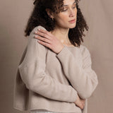 A woman wears a 100% cashmere cropped sweater in beige with white silk shorts