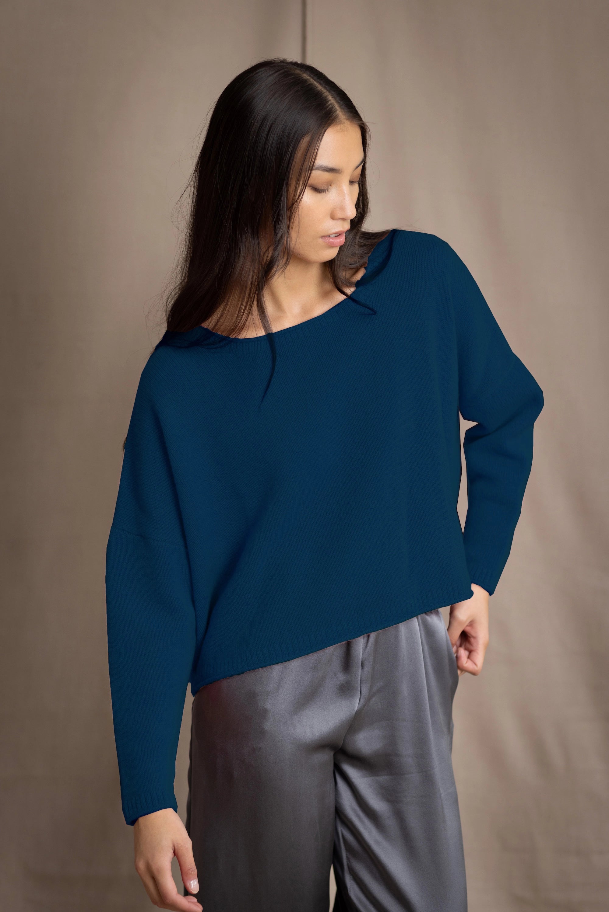 Woman wearing a blue teal cashmere sweater and gray silk pants 
