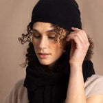 Lady wears luxury cashmere beanie hat in Black with curly hair
