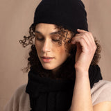 Lady wears luxury cashmere beanie hat in Black with curly hair