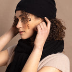 Lady wears luxury cashmere beanie hat in Black with curly hair