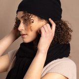 Lady wears luxury cashmere beanie hat in Black with curly hair