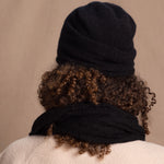 Lady wears luxury cashmere beanie hat in Black with curly hair