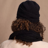 Lady wears luxury cashmere beanie hat in Black with curly hair