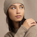 Woman wearing a beige cashmere knit beanie hat with a gold sparkle
