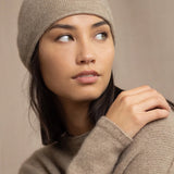 Woman wearing a beige cashmere knit beanie hat with a gold sparkle