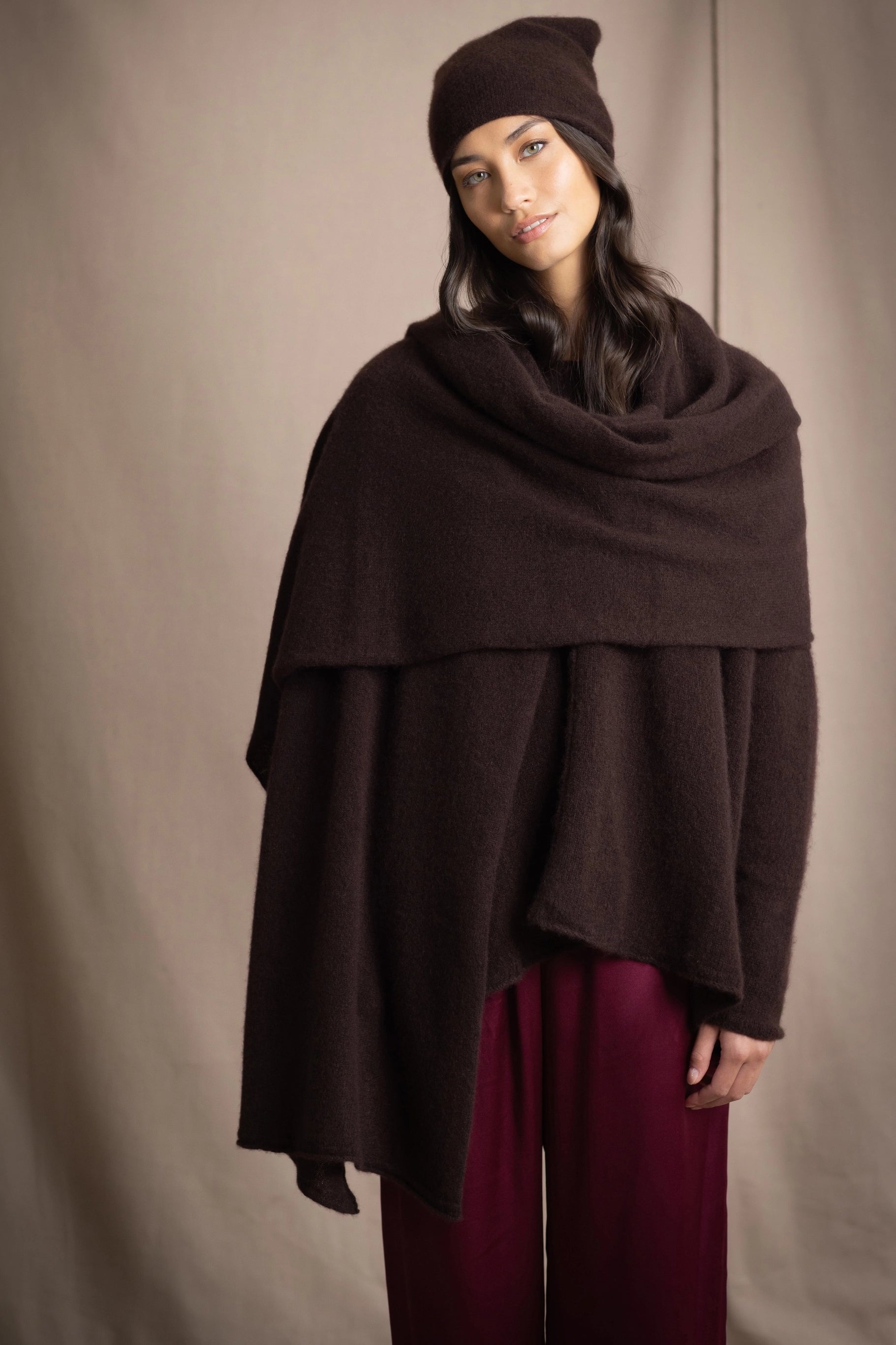 a woman wearing a large cashmere wrap shawl in dark brown with matching cashmere beanie hat