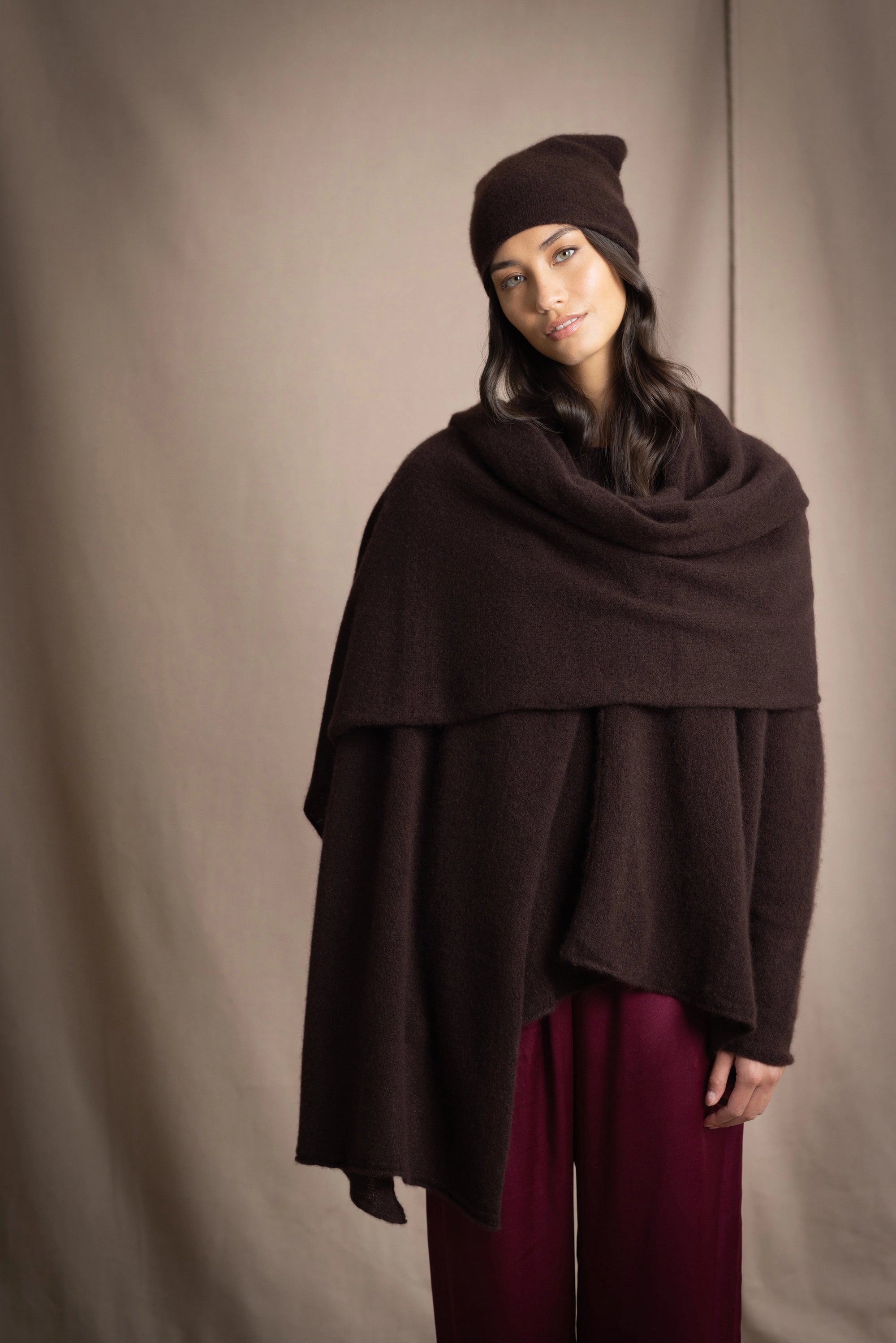 a woman wearing a large cashmere wrap shawl in dark brown with matching cashmere beanie hat
