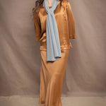 Woman wearing a light turquoise blue cashmere scarf over a bronze silk outfit