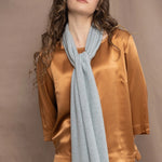 Woman wearing a light turquoise blue cashmere scarf over a bronze silk outfit