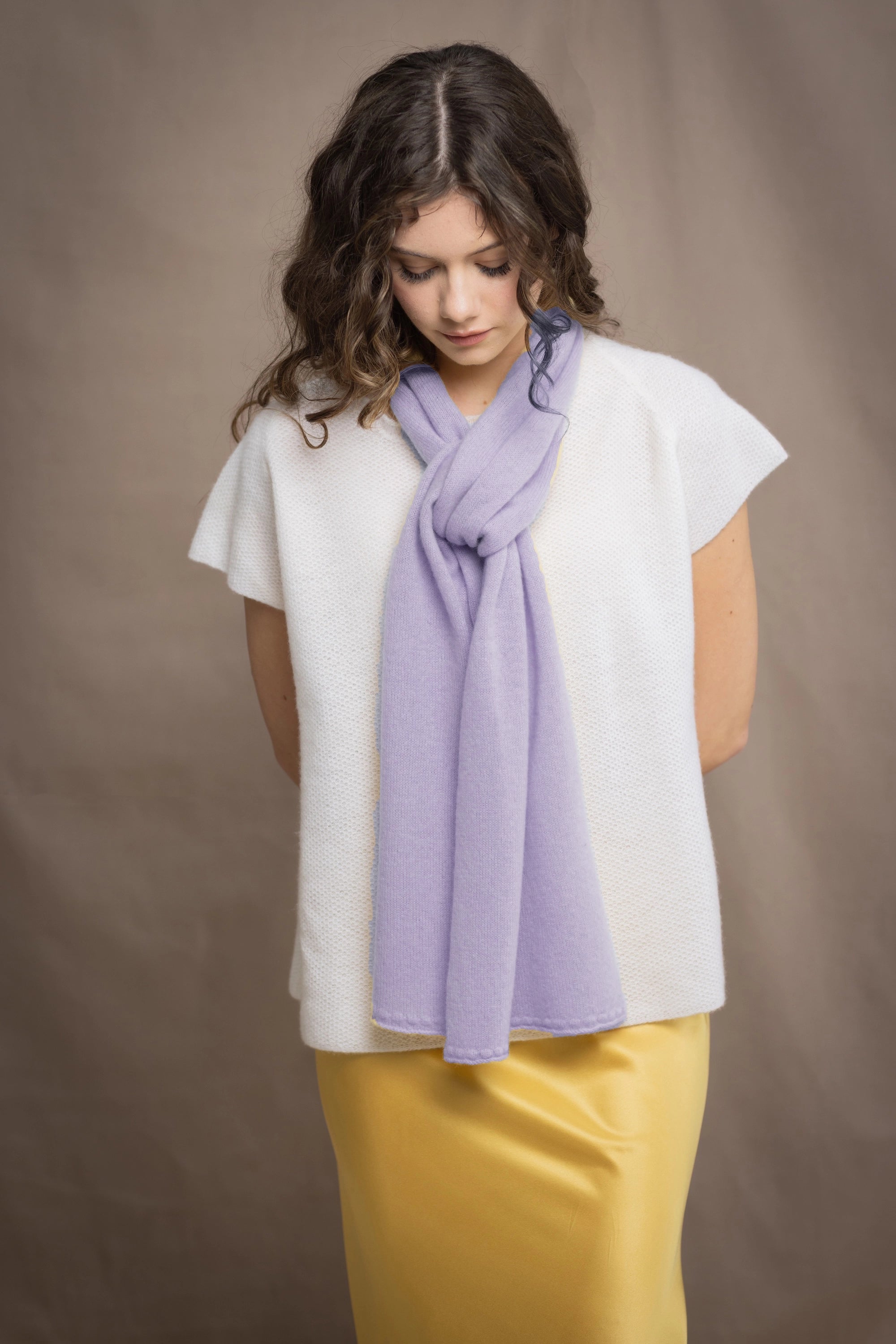 a woman wears a small cashmere scarf in light purple