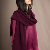 A woman wearing a deep plum burgundy cashmere scarf over burgundy silk clothing