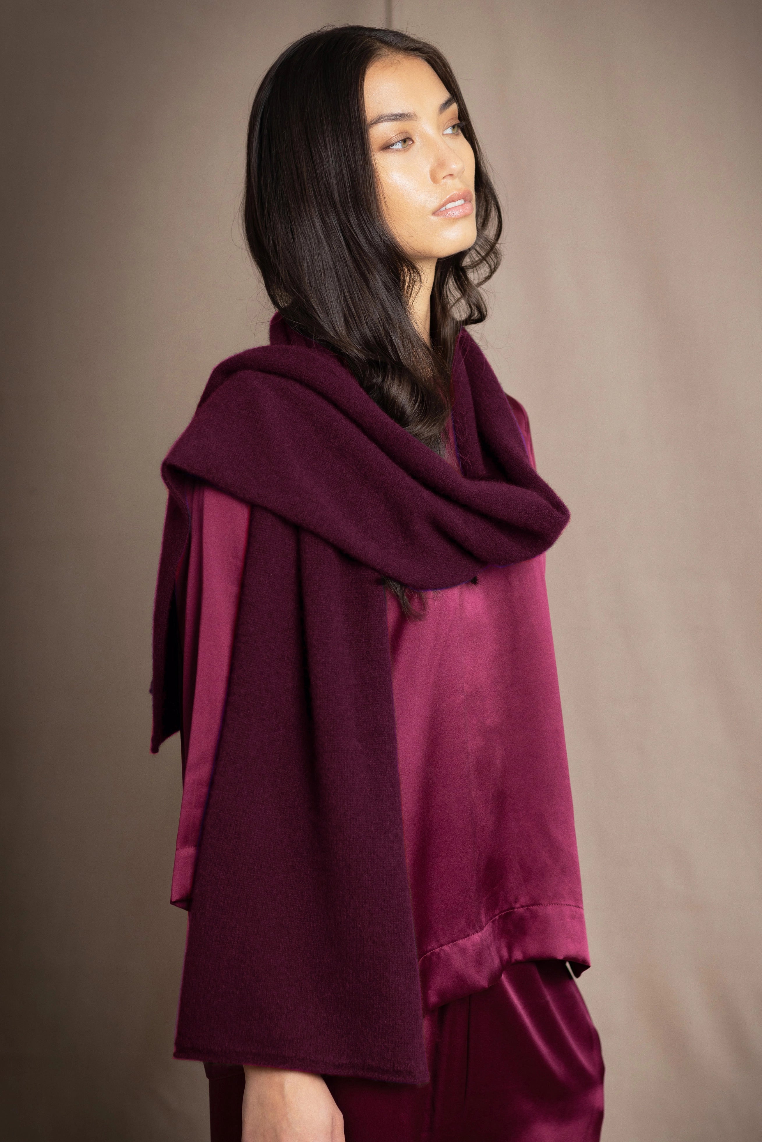 A woman wearing a deep plum burgundy cashmere scarf over burgundy silk clothing