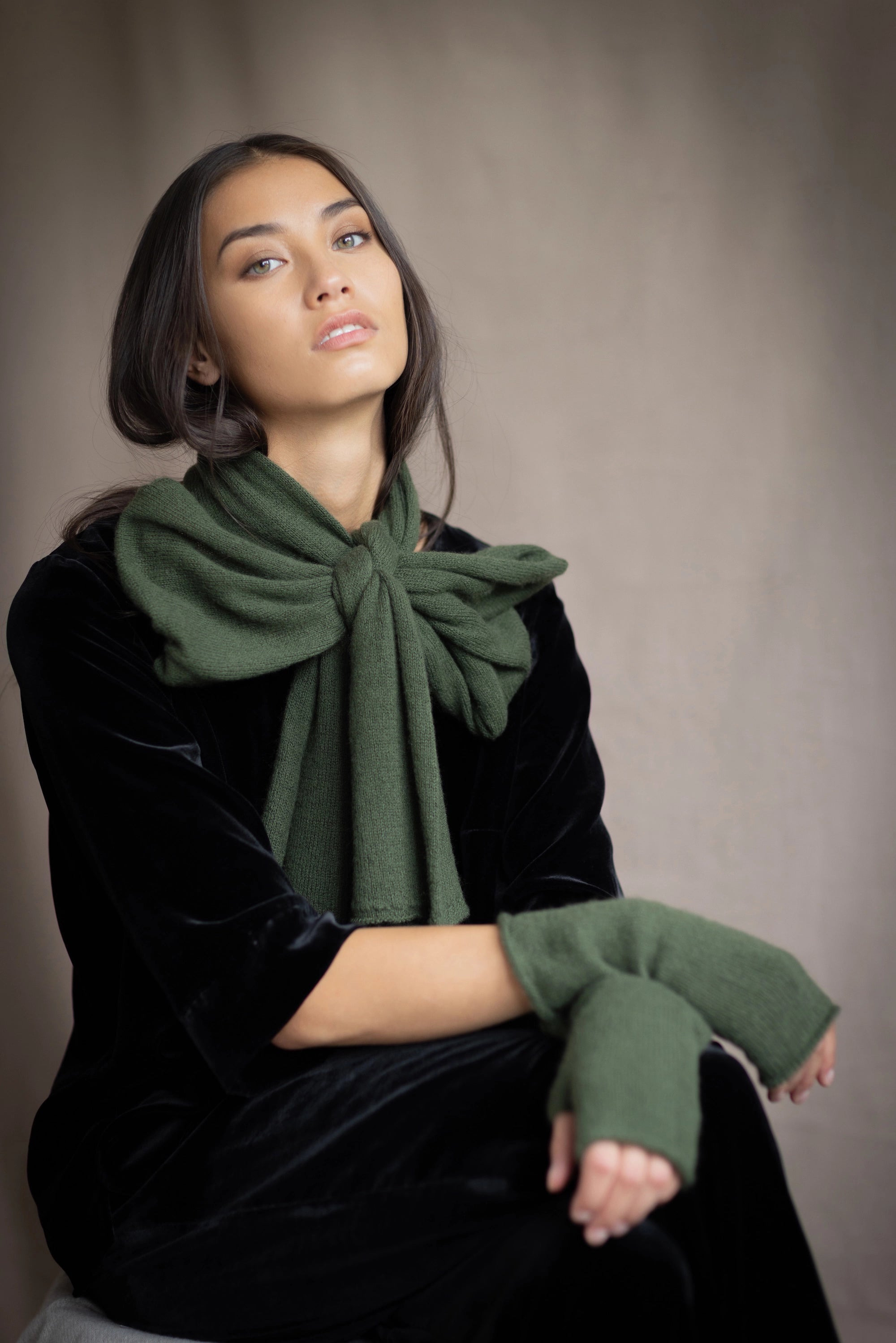 a woman wears a cashmere scarf in green with matching fingerless gloves