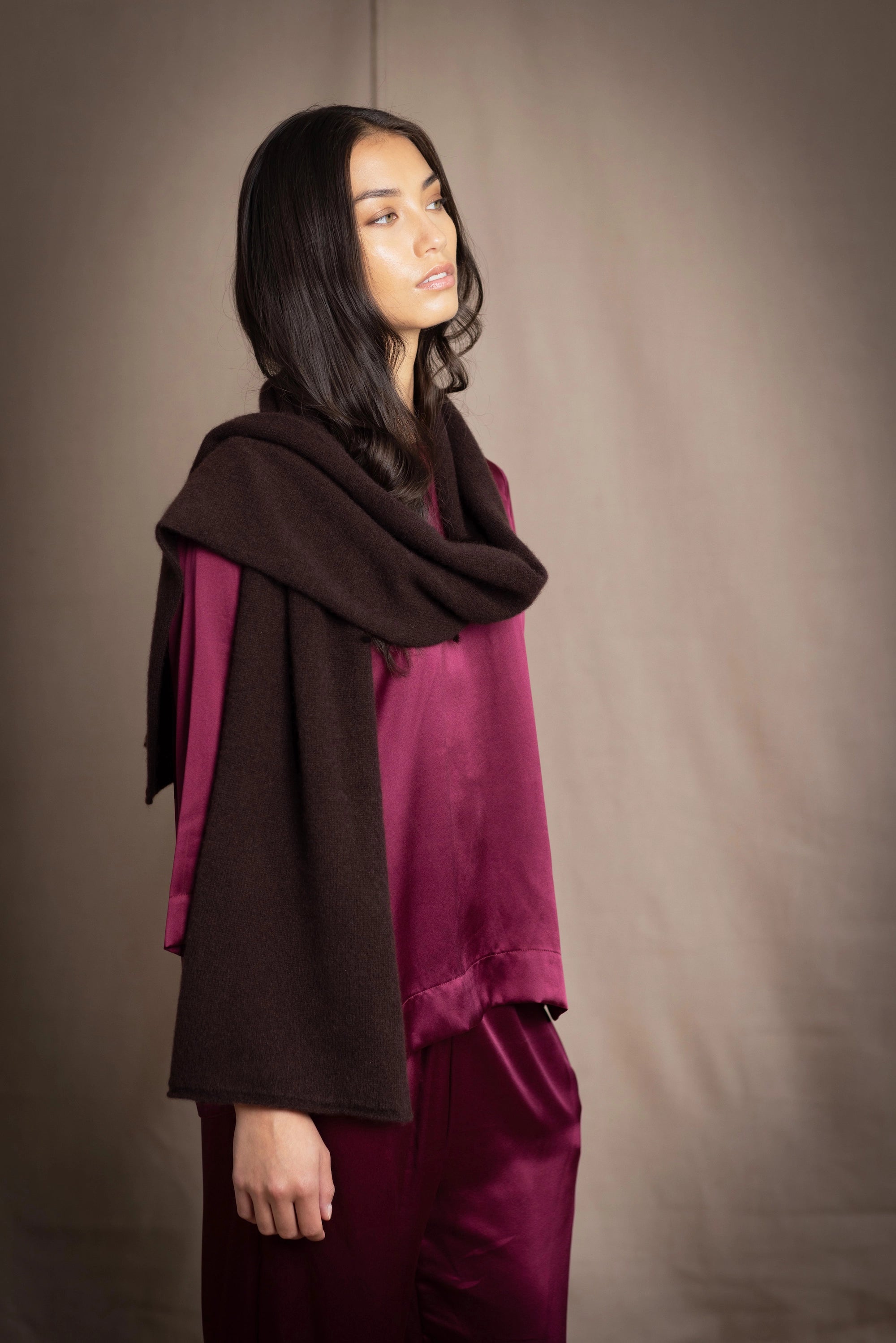 a woman wearing a cashmere scarf in dark brown over burgundy silk clothing