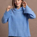 A woman wears a pure 100% cashmere hoodie sweater in blue