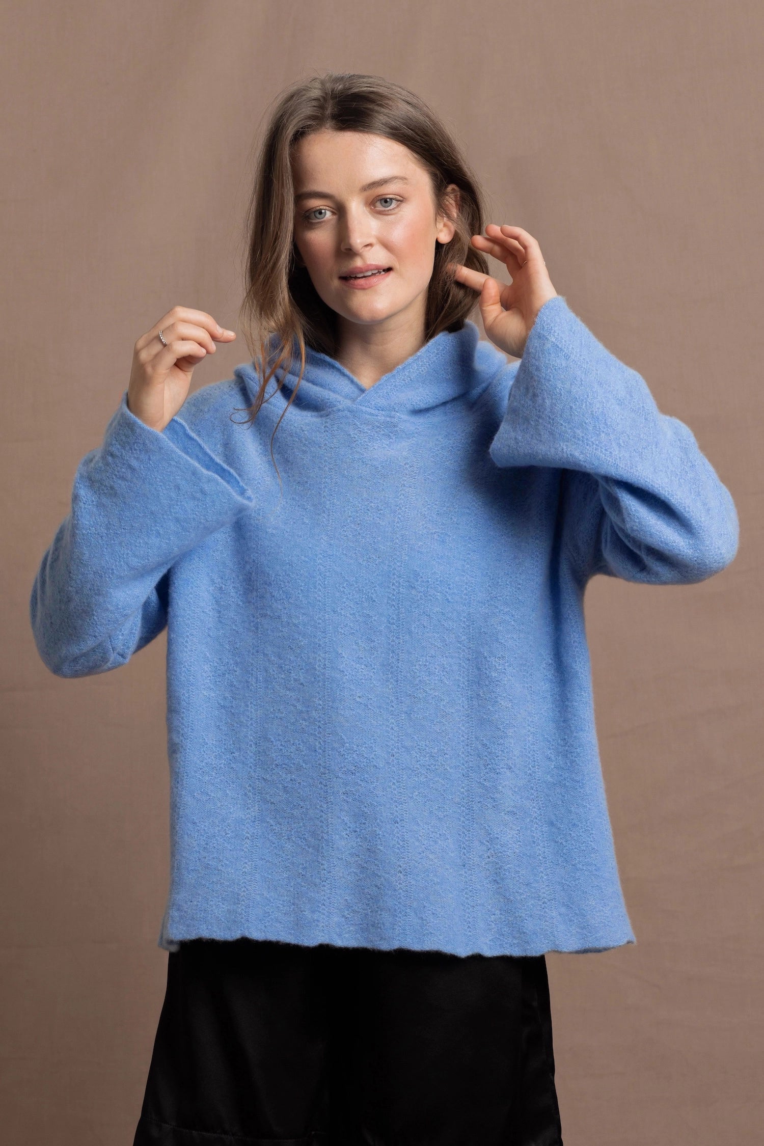 A woman wears a pure 100% cashmere hoodie sweater in blue