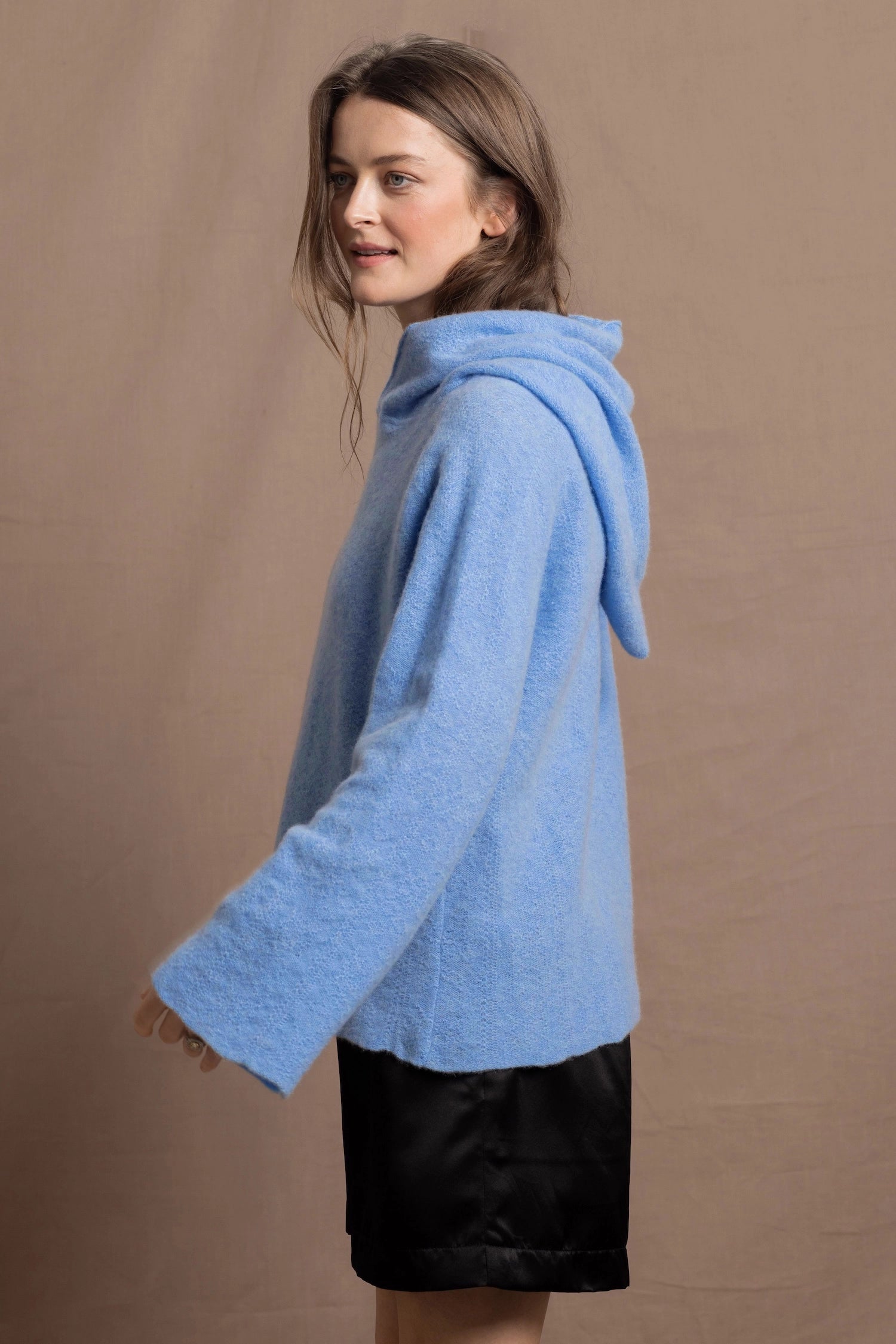 A woman wears a pure 100% cashmere hoodie sweater in blue with black silk shorts