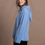 A woman wears a pure 100% cashmere hoodie sweater in blue
