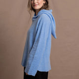A woman wears a pure 100% cashmere hoodie sweater in blue