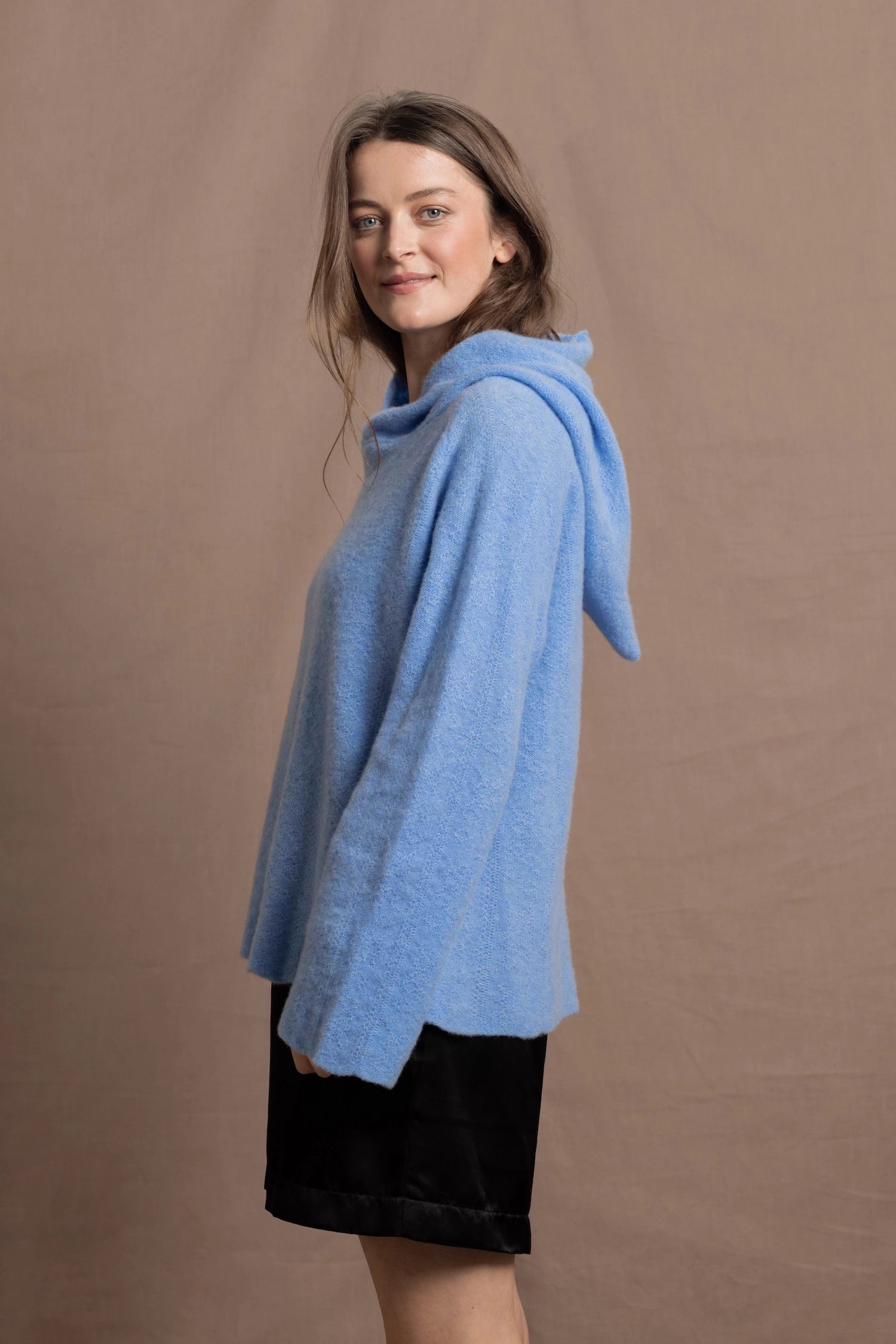A woman wears a pure 100% cashmere hoodie sweater in blue
