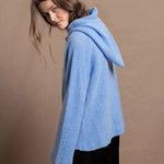 A woman wears a pure 100% cashmere hoodie sweater in blue