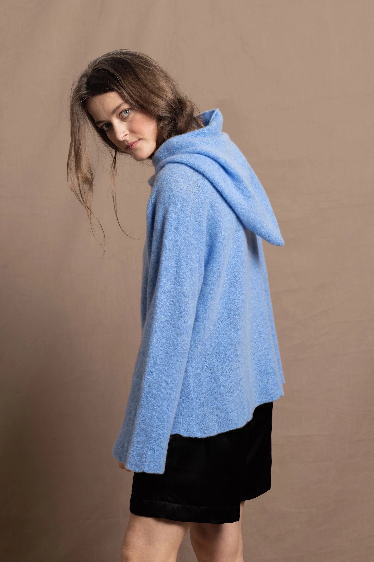 A woman wears a pure 100% cashmere hoodie sweater in blue