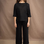 a woman wears an Irish linen top in black with matching black linen trousers by Irish brand Madigan 