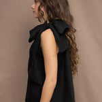 a woman wearing an Irish linen halter top with a bow detail around the neck in black with matching linen trousers by Irish brand Madigan