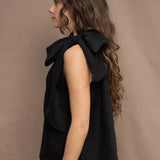 a woman wearing an Irish linen halter top with a bow detail around the neck in black with matching linen trousers by Irish brand Madigan