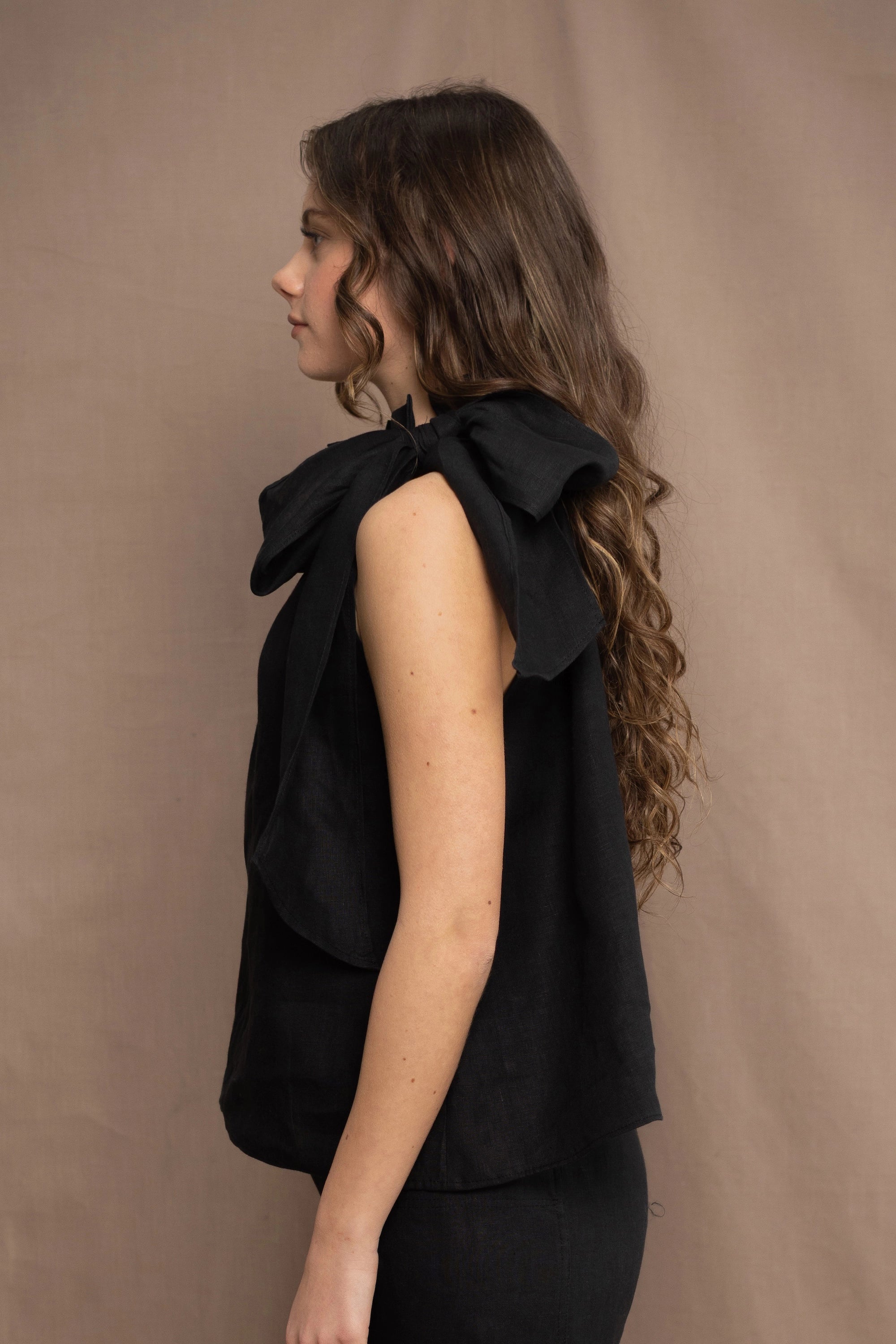 a woman wearing an Irish linen halter top with a bow detail around the neck in black with matching linen trousers by Irish brand Madigan