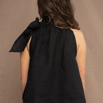a woman wearing an Irish linen halter top with a bow detail around the neck in black with matching linen trousers by Irish brand Madigan