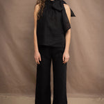a woman wears a black wide leg Irish linen pants or trousers with matching halter neck top by Irish brand Madigan