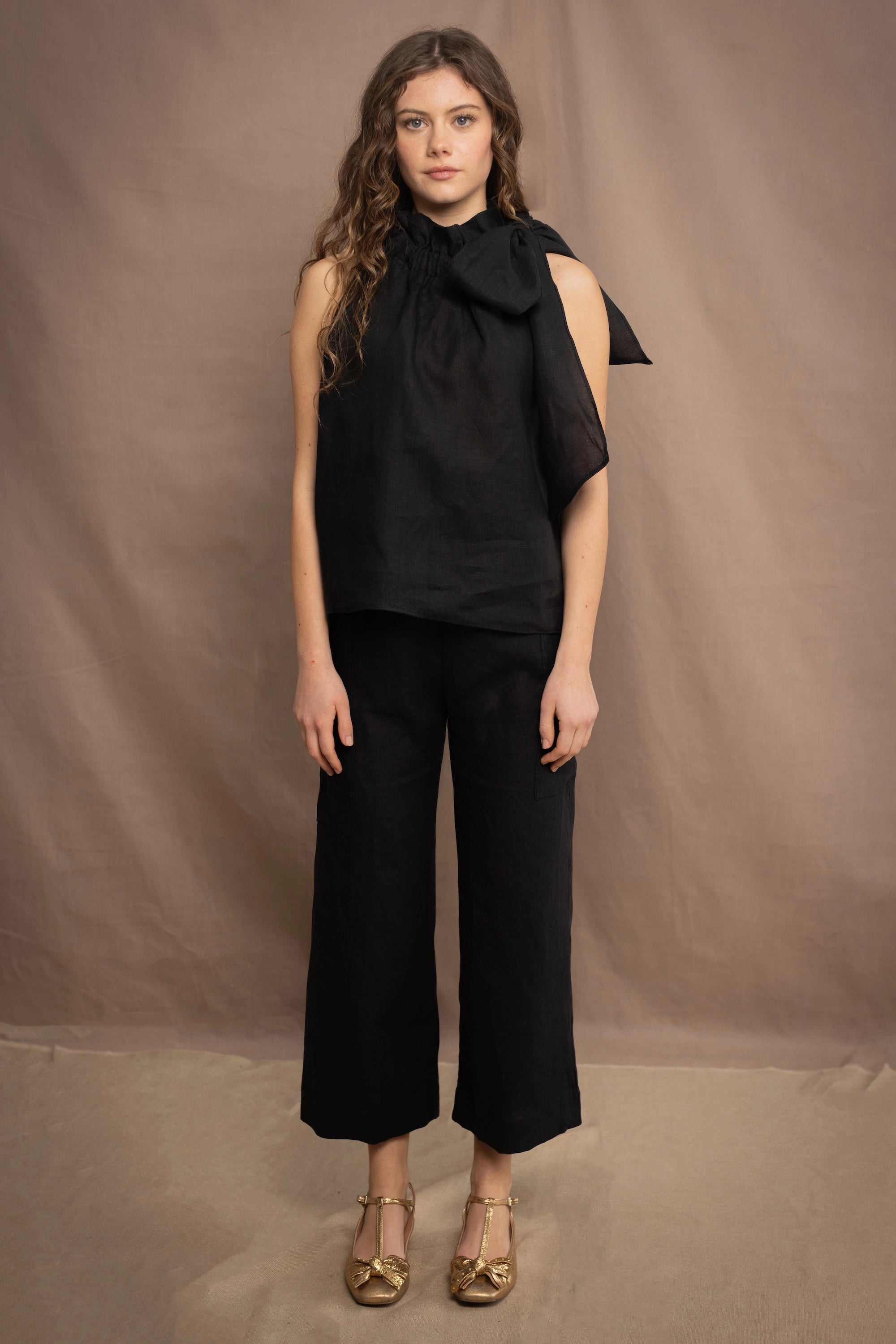 a woman wears a black wide leg Irish linen pants or trousers with matching halter neck top by Irish brand Madigan