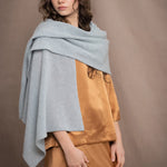 a woman wears a light pale blue turquoise cashmere wrap scarf over bronze silk clothing