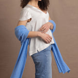 a woman wears a cerulean blue wrap scarf over her elbows paired with a silk white tee and jeans