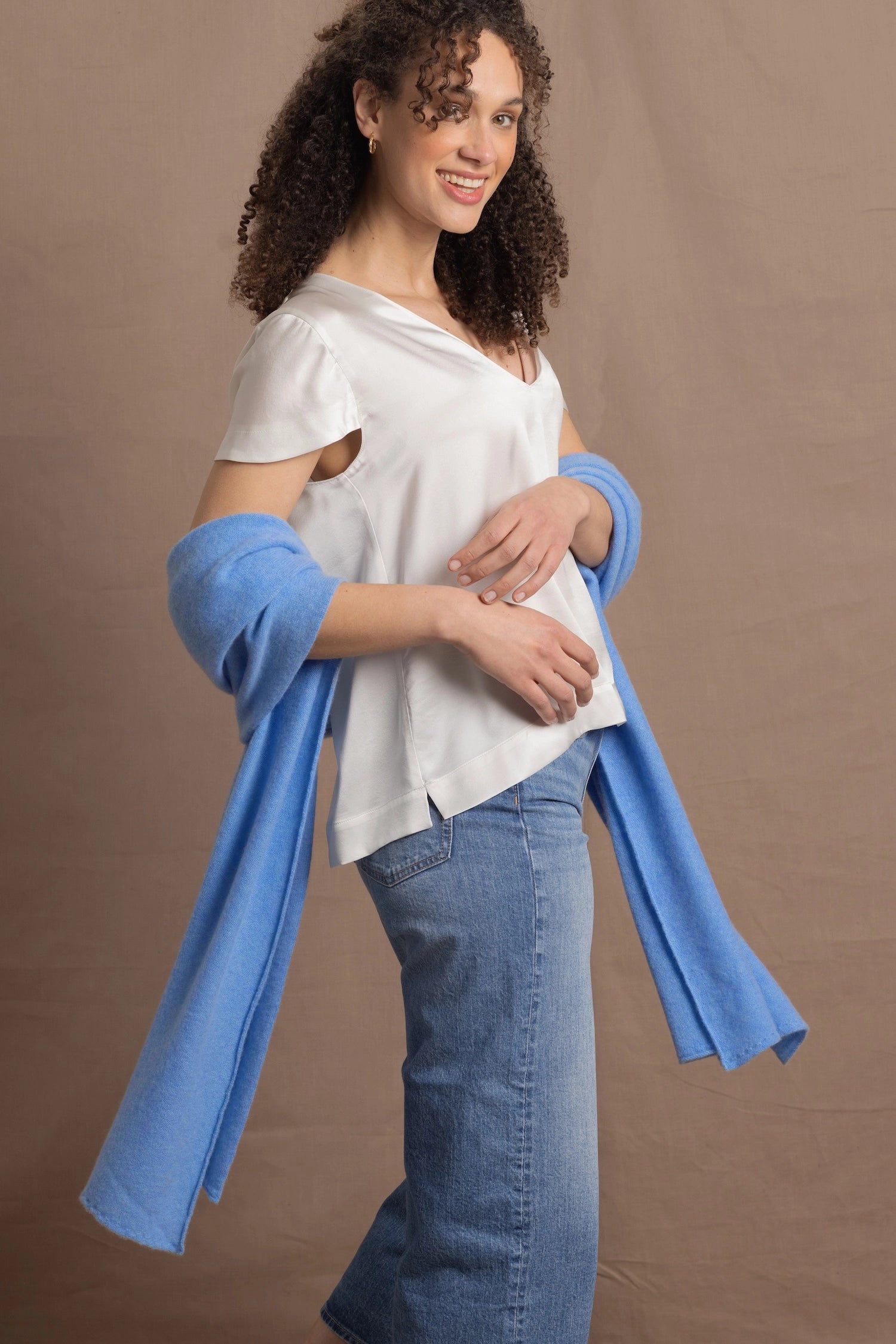 a woman wears a cerulean blue wrap scarf over her elbows paired with a silk white tee and jeans