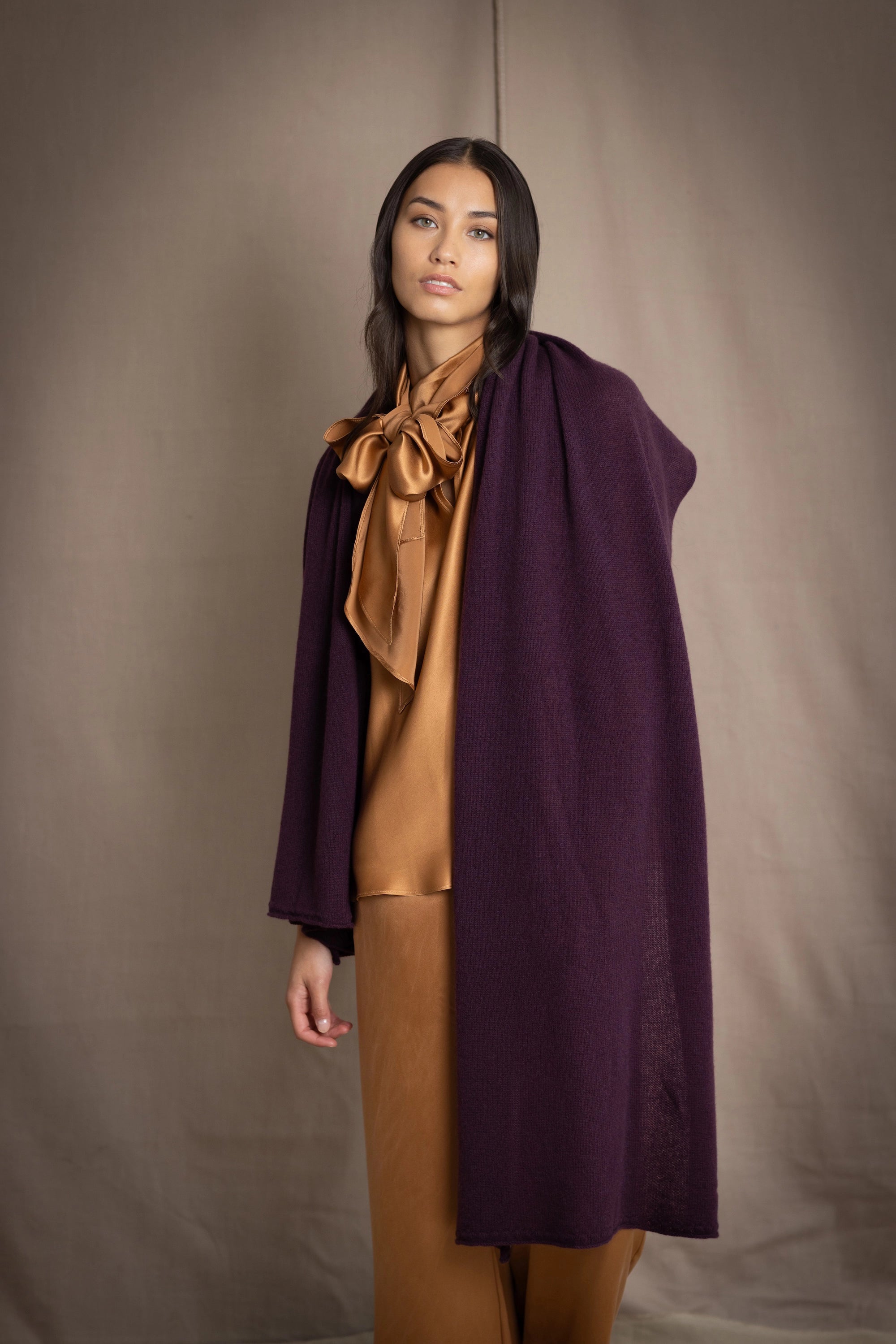 a woman wearing a cashmere wrap scarf in dark purple over bronze silk clothing