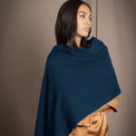 a woman wearing a cashmere wrap scarf in teal over bronze silk clothing
