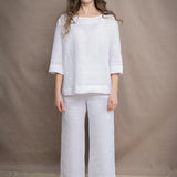 a woman wears a long sleeve pure Irish Linen top in white with matching cropped trousers by Irish brand Madigan 