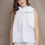 a woman wears an Irish linen halter top with bow detailing on the shoulder in white with matching white linen trousers