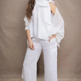 a woman wears a pair of pure Irish linen Cropped trousers and matching halter top in white by Irish brand Madigan