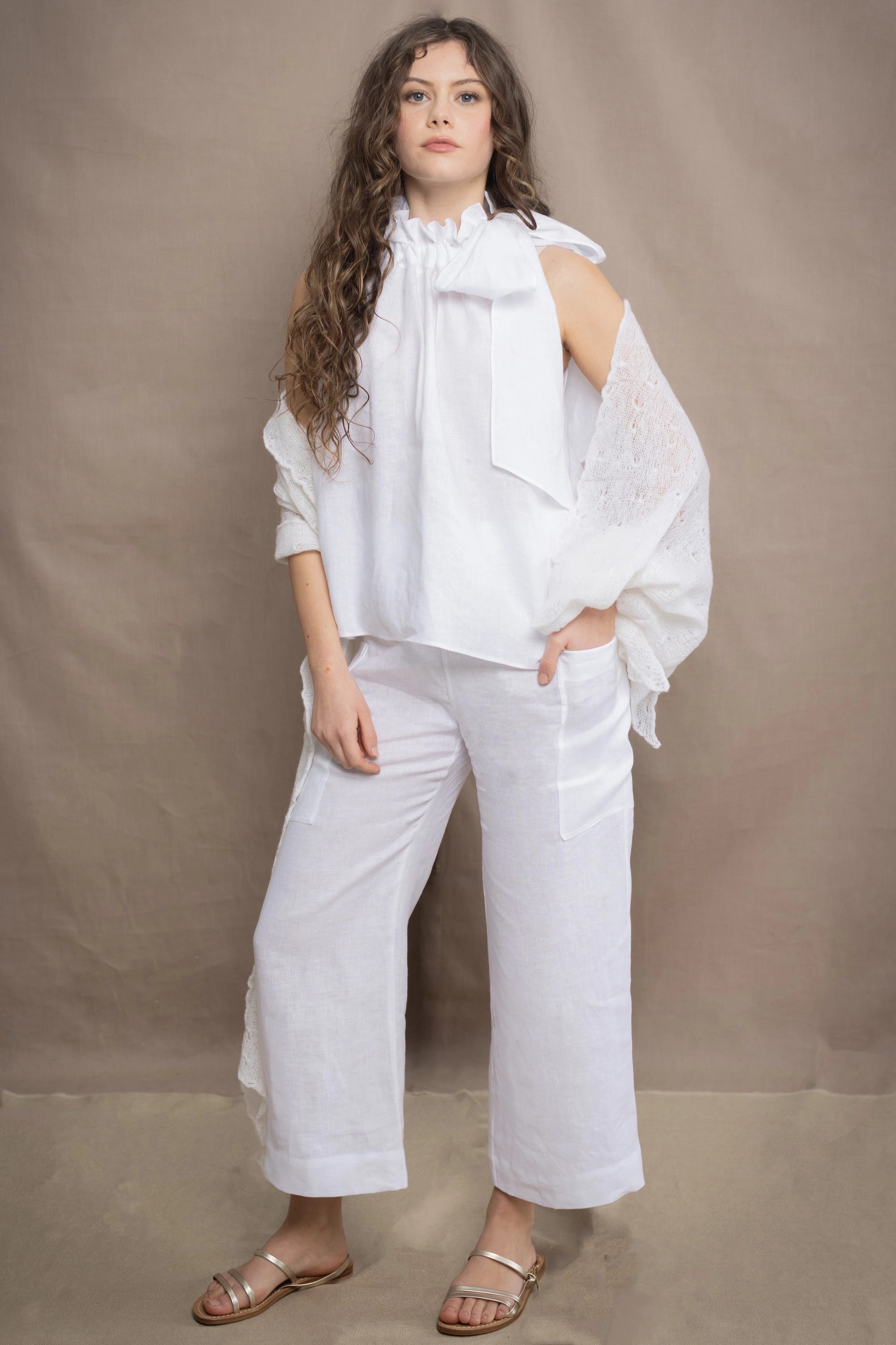 a woman wears a pair of pure Irish linen Cropped trousers and matching halter top in white by Irish brand Madigan