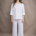 a woman wears a pair of pure Irish linen Cropped trousers and long sleeve top in white by Irish brand Madigan