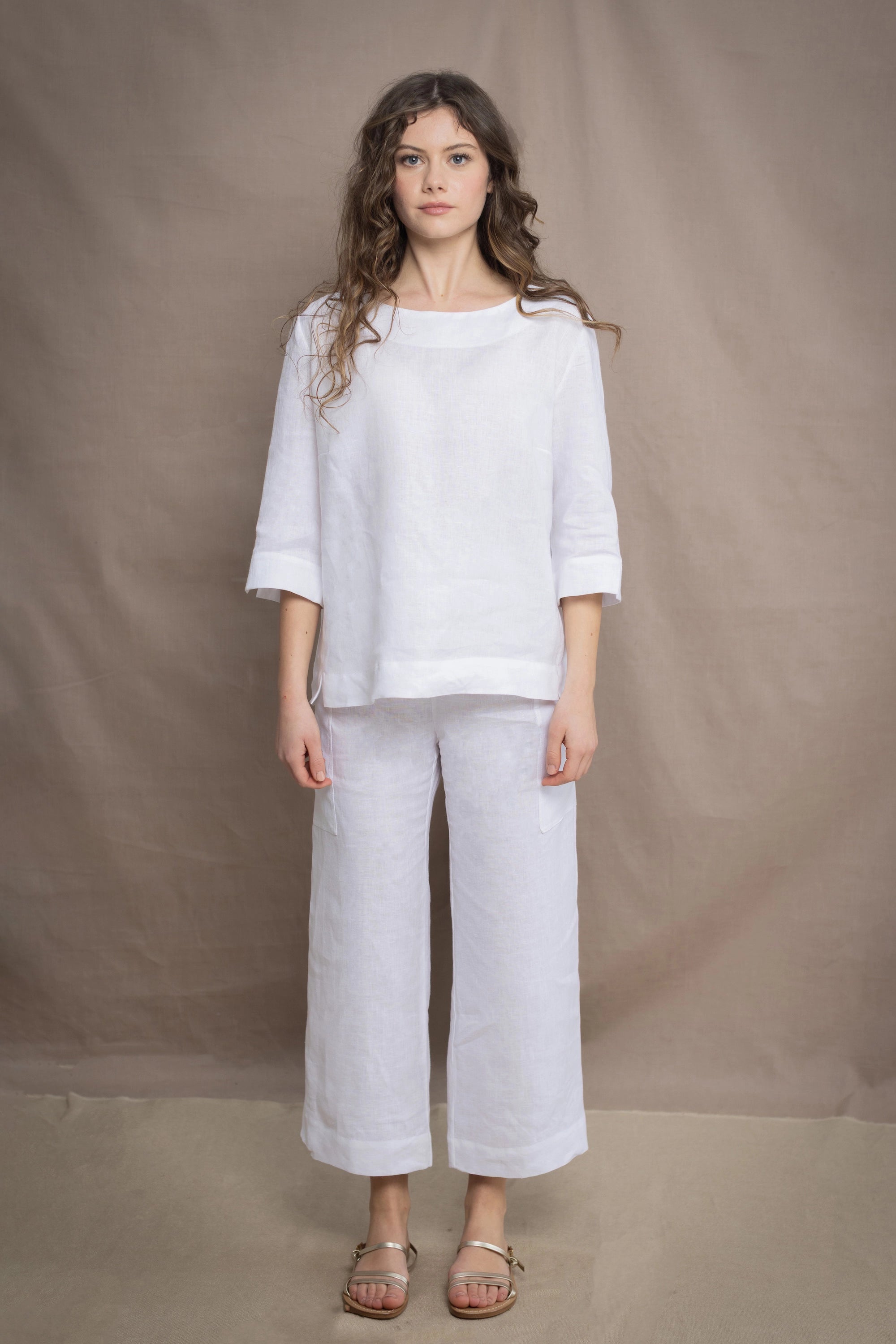 a woman wears a pair of pure Irish linen Cropped trousers and long sleeve top in white by Irish brand Madigan
