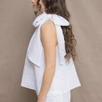 a woman wears an Irish linen halter top with bow detailing on the shoulder in white with matching white linen trousers 